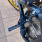 Installed black front folding foot peg and clamp on motorcycle frame