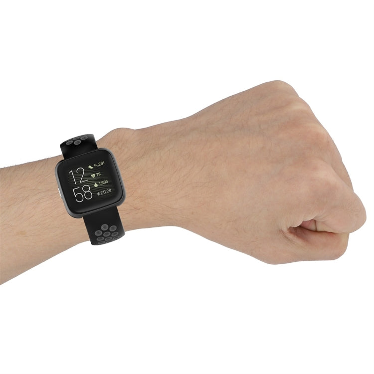 Sport watch band worn on wrist, dark strap with perforated pattern and metal clasp