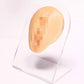 Flesh-tone silicone facial feature insert on clear stand with pixelated detail