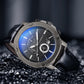 Men's multifunction watch close-up with black leather strap, dark dial, blue luminous-style highlights.