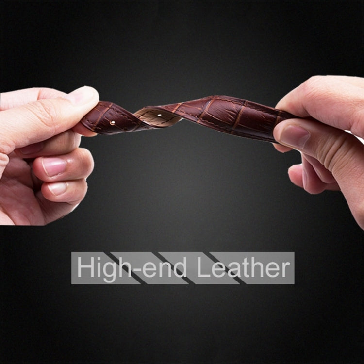 Dark brown leather watch band with crocodile texture and steel buckle end, held by hands