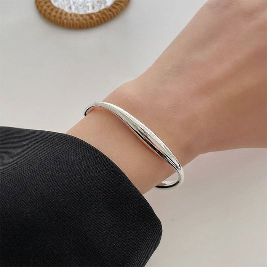 Sterling silver open bangle bracelet on wrist, smooth polished cuff style