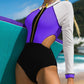 Long-sleeve one-piece swimsuit, white and purple panels with black center zipper.
