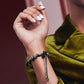 Black ribbon wave metal watch band worn on wrist, chain with charm