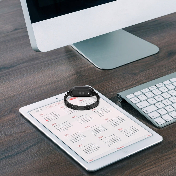 Black link replacement watch band with fitness tracker placed on a desk surface