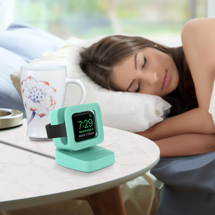 Mint green watch stand on bedside table with smartwatch display