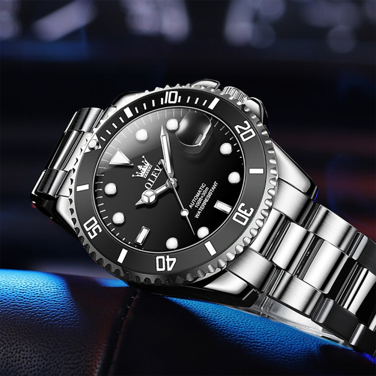 Angled close-up of men's mechanical waterproof wristwatch with black dial, luminous markers, steel bracelet