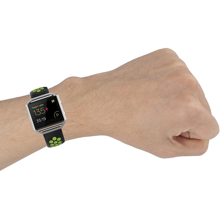 Silicone sports watch strap on wrist in black with green accent perforation pattern