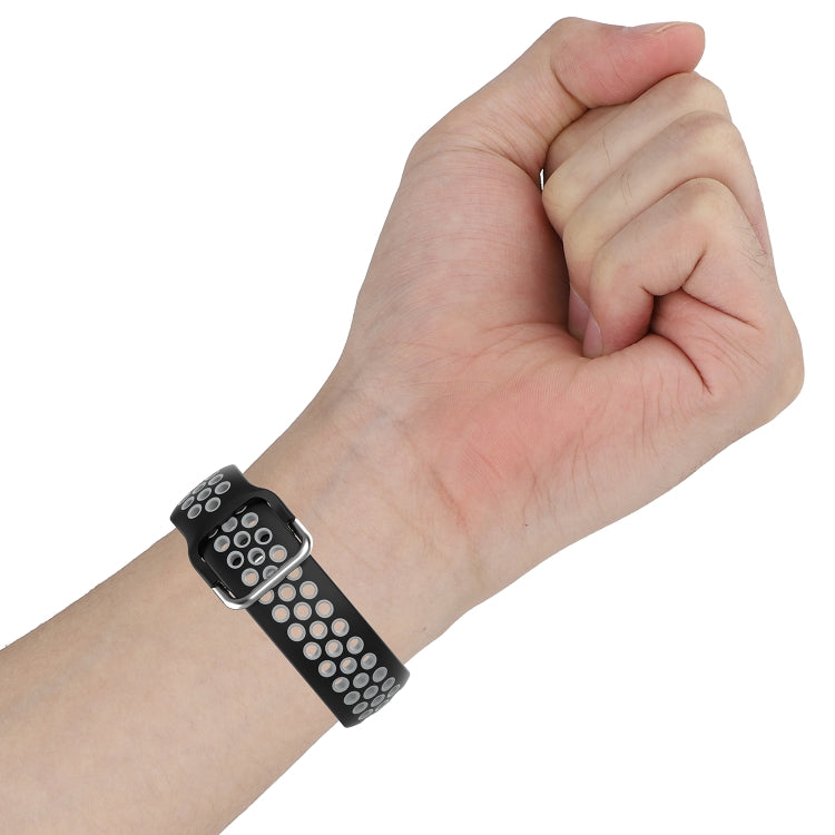 Silicone sports watch strap on wrist, black with perforated gray/white dot pattern