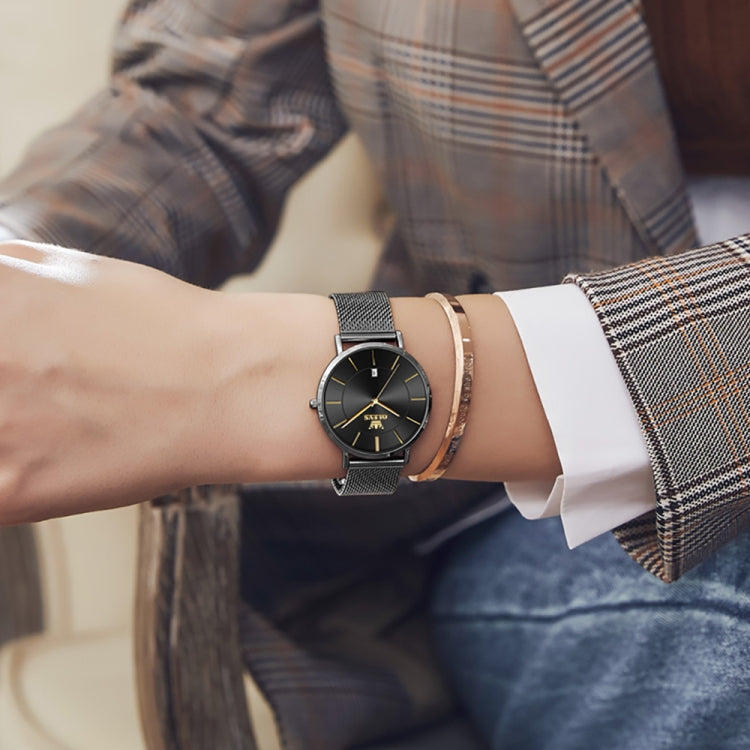 Black dial quartz watch on wrist with black mesh steel strap in business attire