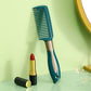 Curly hair massage comb with teal bristles, copper-toned handle, and finger grips