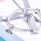 Sterling silver bracelet with blue bird charm and ribbon-tied clasp detail