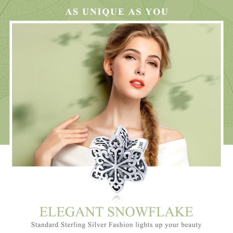 Snowflake charm bead held near off-shoulder top, sterling silver filigree design
