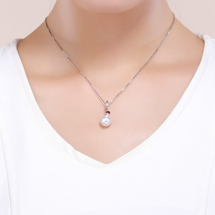Wearing silver necklace pendant with red heart gem and white pearl drop