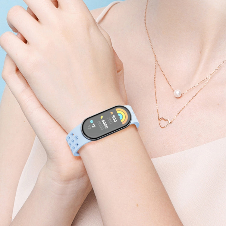 Light blue perforated watch band worn on the wrist with a fitness tracker