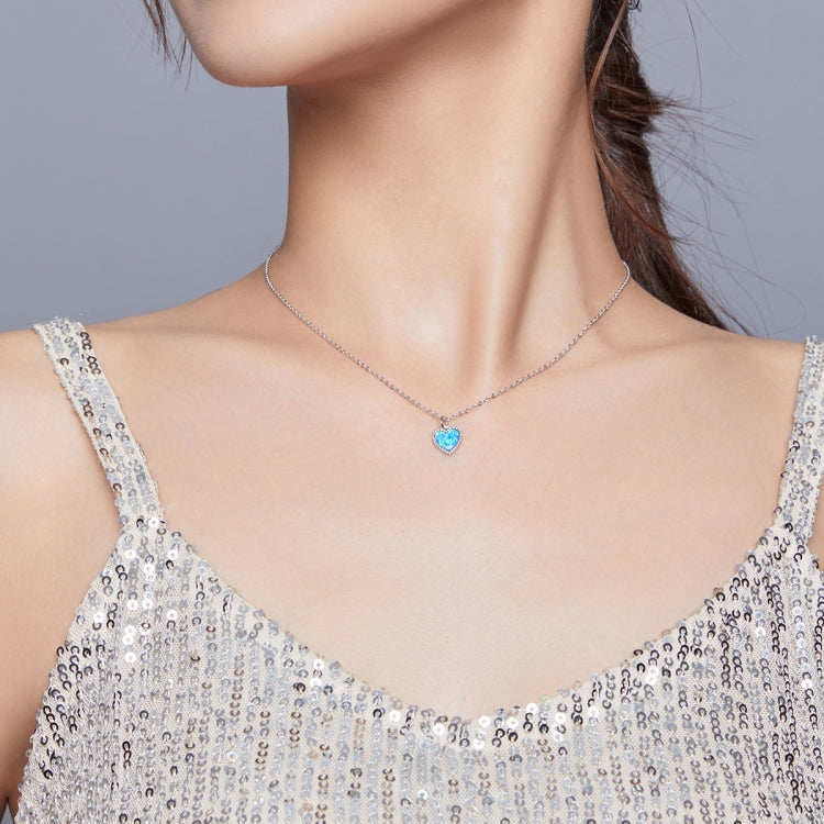 Sterling silver heart pendant necklace with deep blue gemstone centered on chain