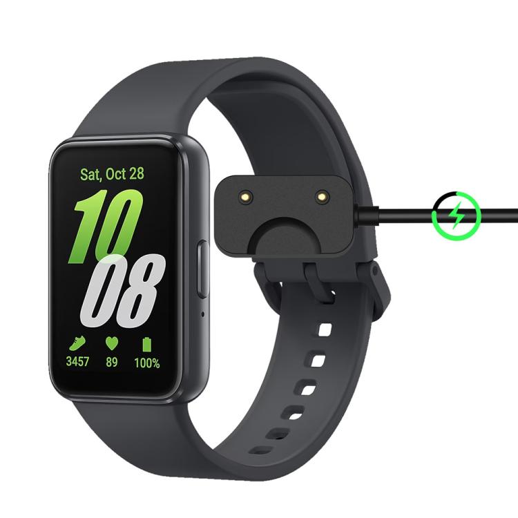 Galaxy Fit3 smartwatch connected to its black magnetic charging cable