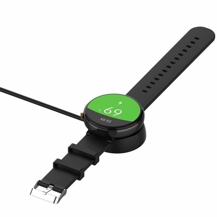 Black smartwatch seated on its round charging dock, connected to the cable