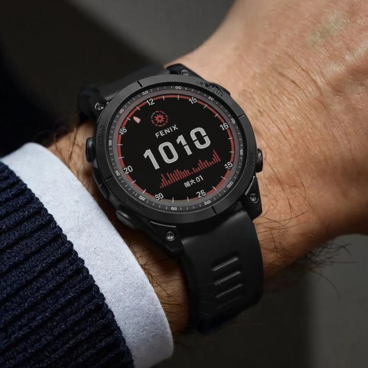 Black Garmin sports watch with a black silicone band worn on the wrist