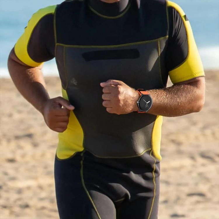 Orange watch band worn with a round smartwatch during activity
