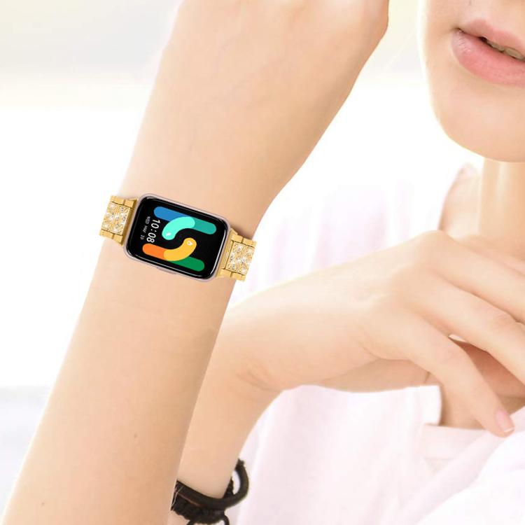 Gold crystal-accented stainless steel watch band worn on the wrist