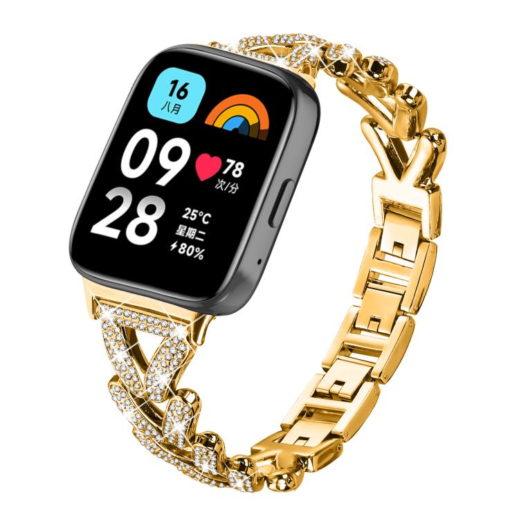 Gold-tone metal smartwatch band with rhinestone-set twisted links, shown attached to a watch.