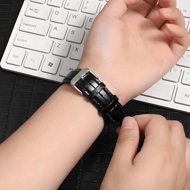 Black textured leather watch band with silver pin buckle, worn on a wrist.