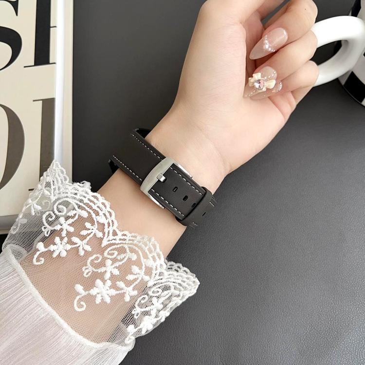 Black leather watch band with white stitching and a silver buckle worn on a wrist.