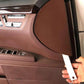 White trim removal tool held by hand near an interior panel edge