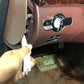 White trim removal tool held by hand, prying at an interior panel opening