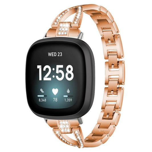 Rose gold metal Fitbit watch band with crystal accents shown on a smartwatch.