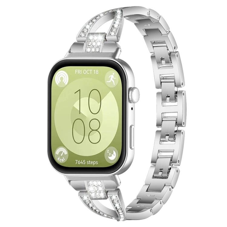 Silver X-shaped metal watch band with crystal accents, shown attached to a smartwatch.