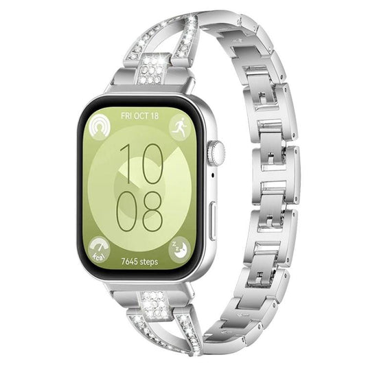 Silver X-shaped metal watch band with crystal accents, shown attached to a smartwatch.