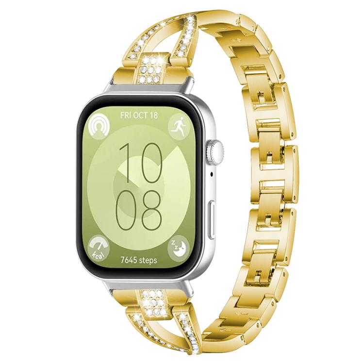 Gold X-shaped metal watch band with crystal accents, shown attached to a smartwatch.