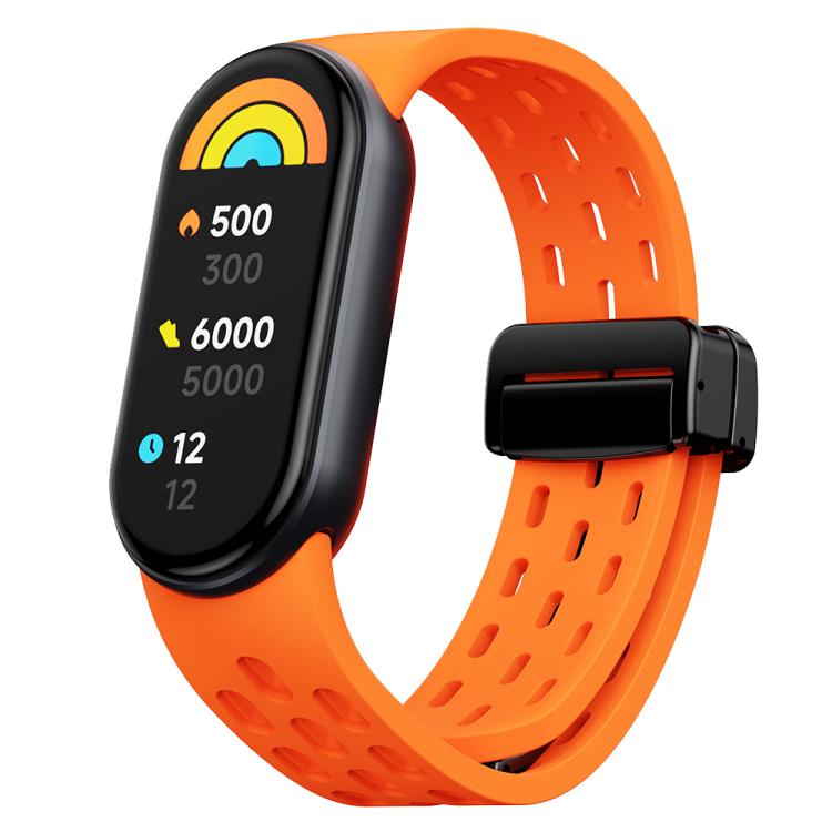Orange perforated silicone watch band with black magnetic clasp, shown with a fitness tracker