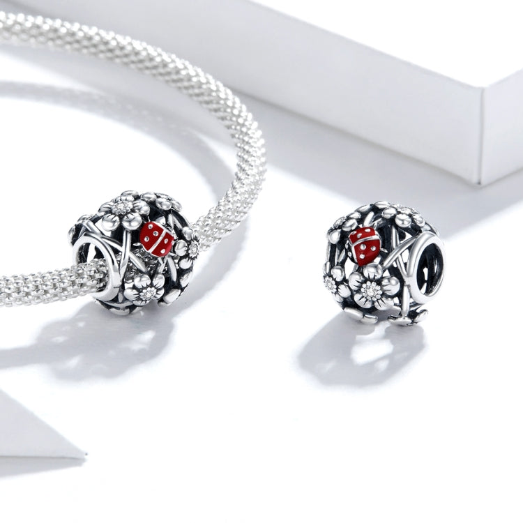 Charm bead on silver chain with red ladybug enamel and flower filigree.
