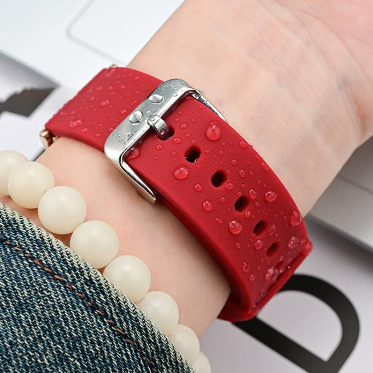 Red silicone watch band worn on a wrist, with water droplets on the band and silver buckle