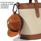 Tan and brown cap-style coin purse with zip closure and metal snap button