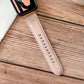 Light pink leather-look watchband with metal buckle and perforated strap holes