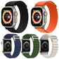 Five nylon loop bands in assorted colors fitted to Apple Watches, shown from front and back