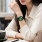 Square quartz watch worn on wrist with green dial and black nylon band