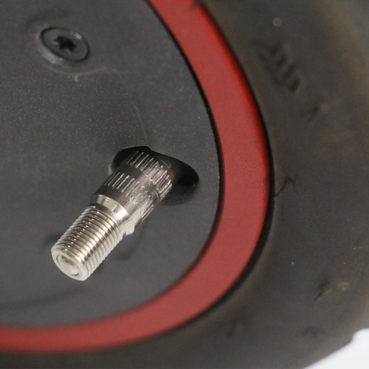 Close-up of scooter wheel air valve with metal threaded stem on rim