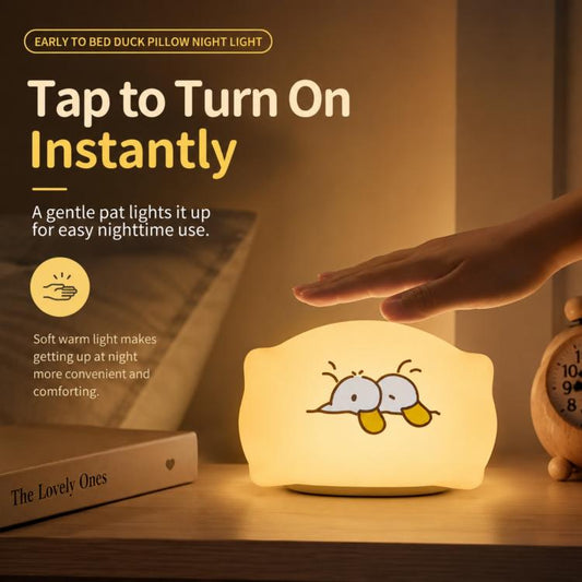 Pillow duck night light emitting a warm light with a hand reaching to tap