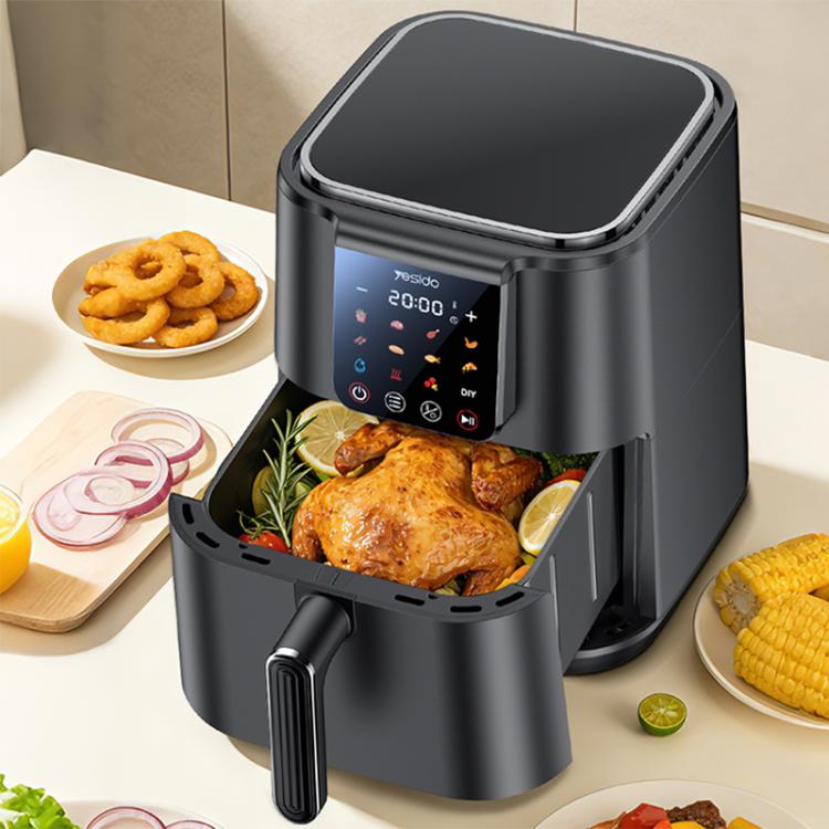 Black 6L air fryer with open basket and touch screen control, roasted chicken inside