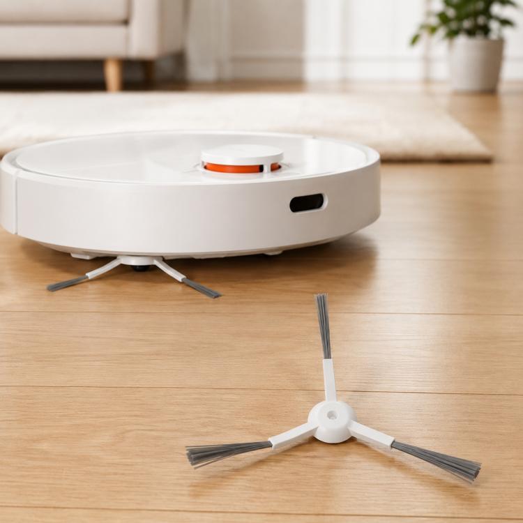 Robot vacuum base with two white side brushes and a spare brush on floor