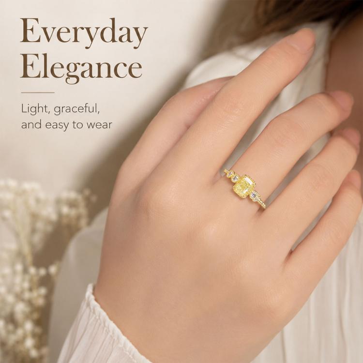 Gold-tone square ring with yellow center stone and clear side stones on slim band.