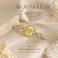 Gold-tone geometric ring with square yellow center stone and round clear side stones.