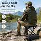Black folding camping chair with zippered storage bag beside a seated angler