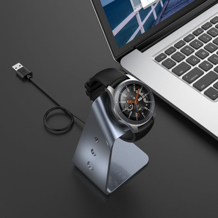 Grey charging stand with USB cable docked to a smartwatch