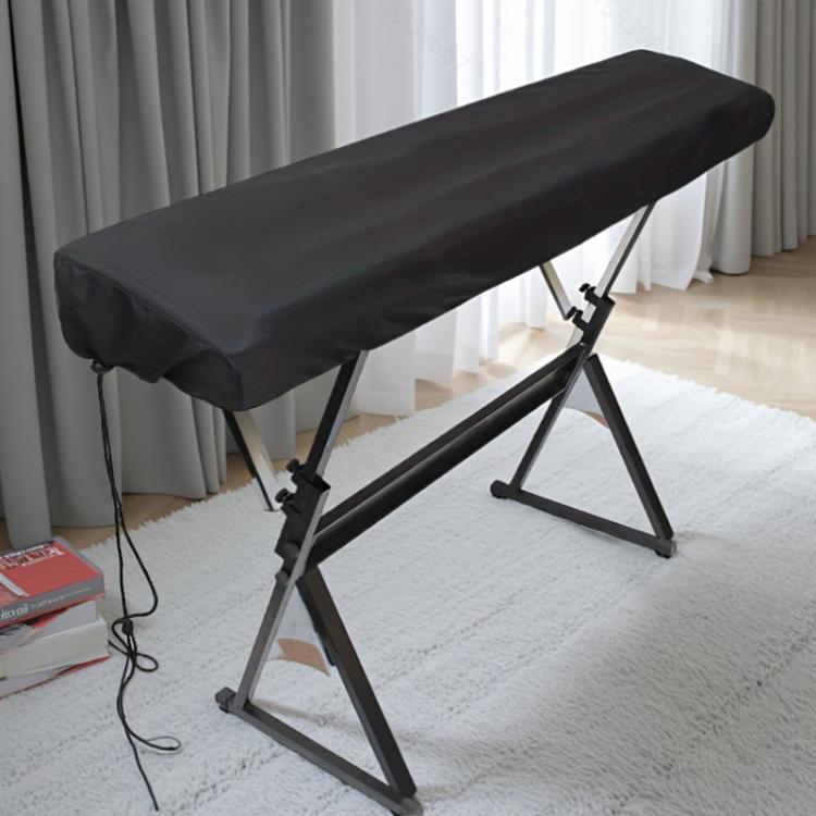 Black dustproof piano keyboard cover with drawstring, fitted over electronic keyboard stand.
